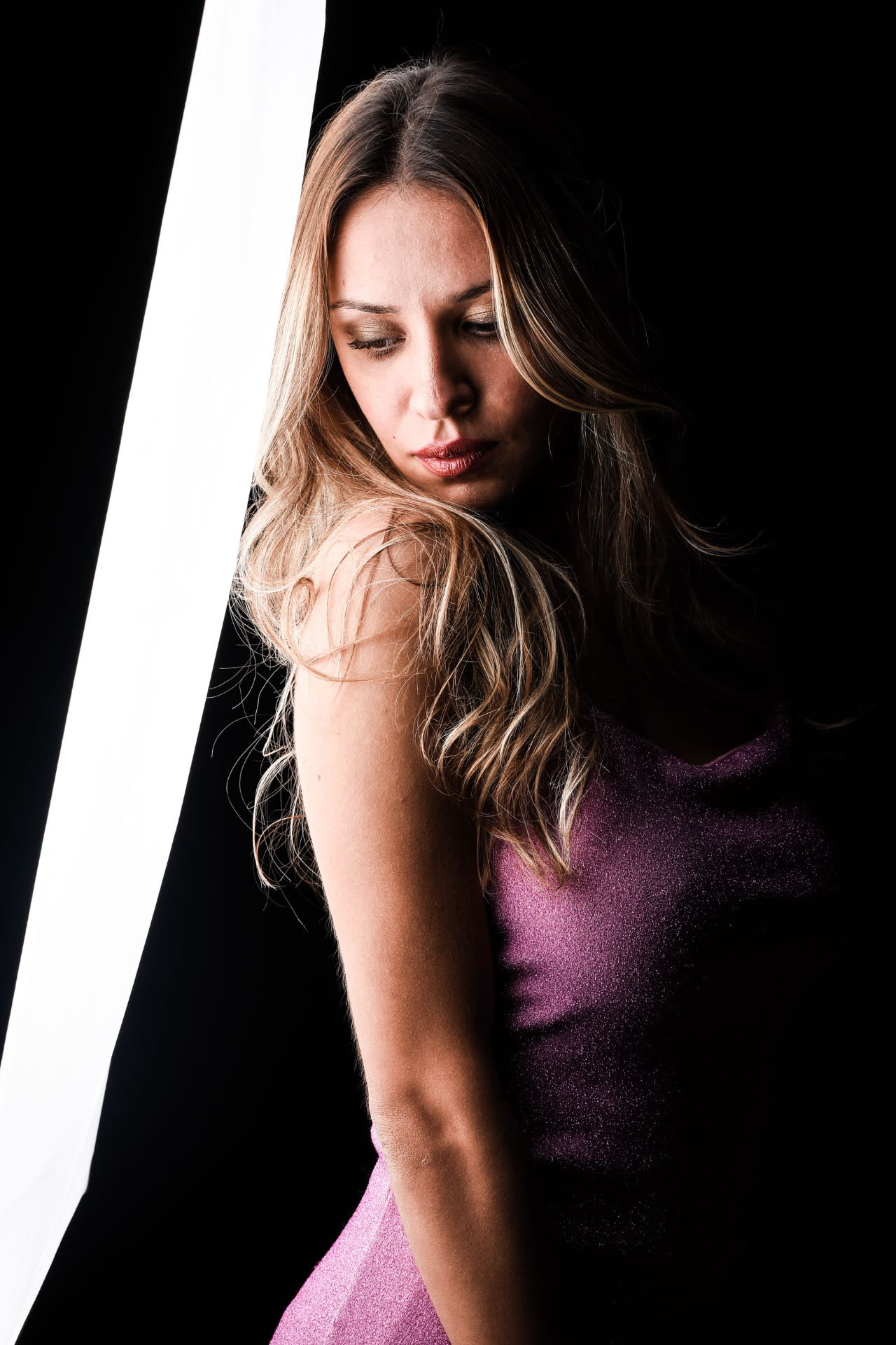 Ritratto in studio di donna bionda con abito viola e luce scolpita