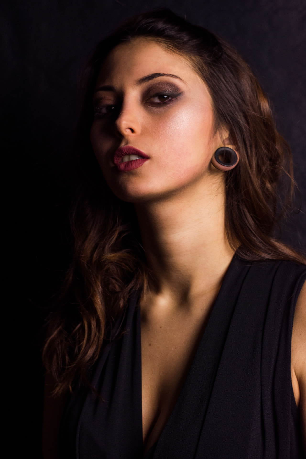 Ritratto in studio di donna dai capelli castani su fondo nero, luce morbida laterale