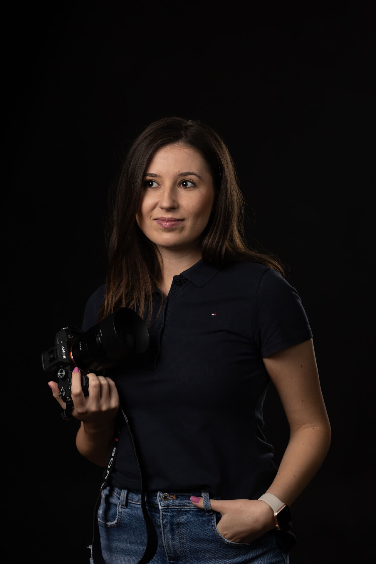 Ritratto di fotografa con fotocamera in mano su sfondo scuro